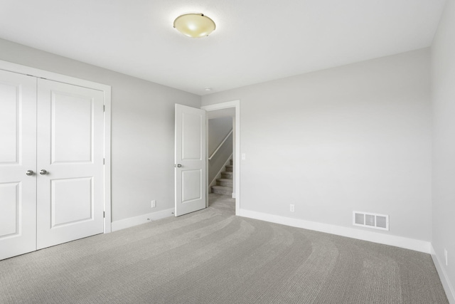 unfurnished bedroom featuring light colored carpet and a closet