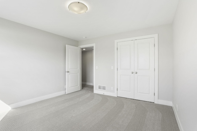 unfurnished bedroom with a closet and light colored carpet