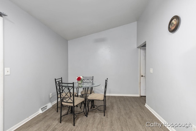 dining area featuring wood-type flooring and vaulted ceiling