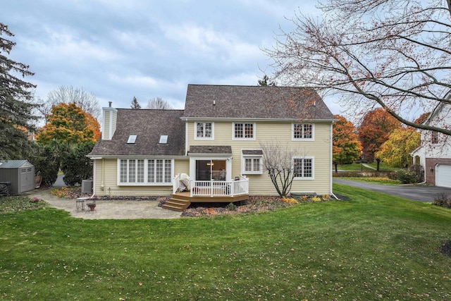 back of property with a storage shed, a patio area, a lawn, and a deck