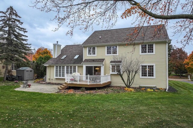 rear view of property featuring a patio area, a yard, a deck, and a storage unit