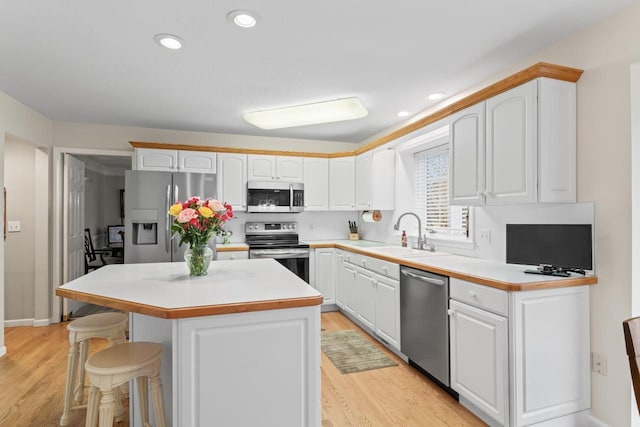 kitchen featuring white cabinetry, sink, a kitchen island, and appliances with stainless steel finishes