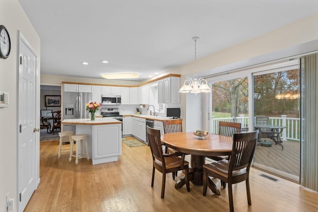 dining room featuring sink, a chandelier, and light wood-type flooring