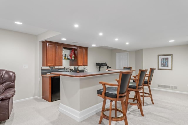 kitchen with light carpet, a kitchen breakfast bar, and kitchen peninsula