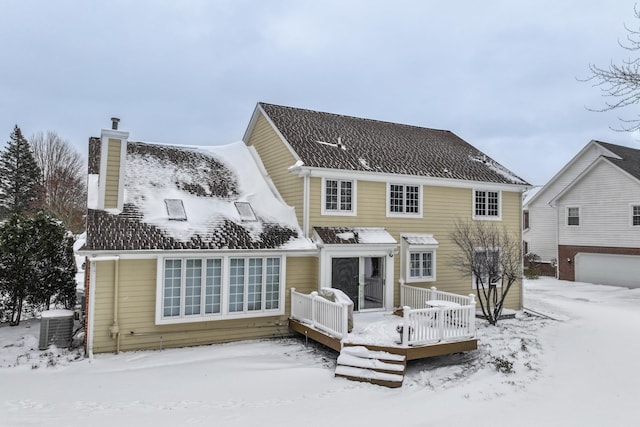 snow covered rear of property featuring cooling unit and a wooden deck