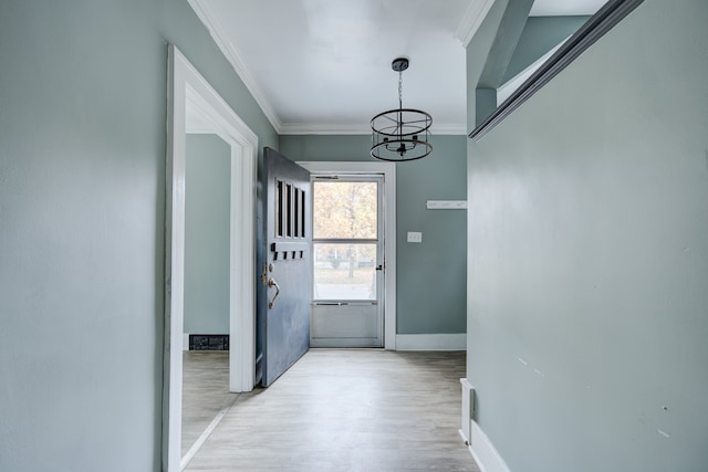 doorway featuring a chandelier, light hardwood / wood-style floors, and ornamental molding