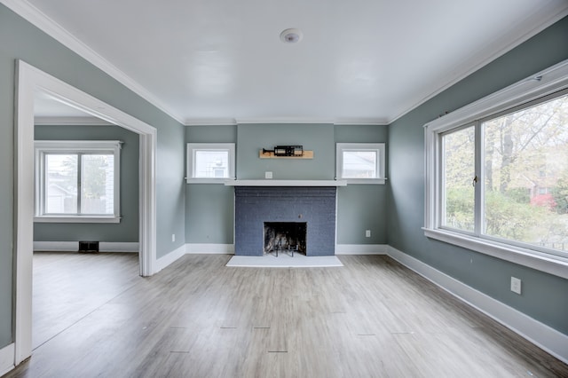 unfurnished living room with a fireplace, light wood-type flooring, crown molding, and a healthy amount of sunlight