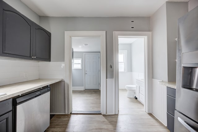 kitchen with light wood-type flooring, stainless steel appliances, and backsplash