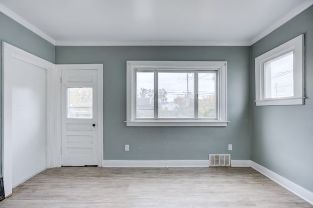 entrance foyer featuring ornamental molding, a healthy amount of sunlight, and light wood-type flooring