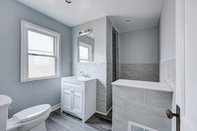 bathroom with vanity, toilet, wood-type flooring, and tile walls