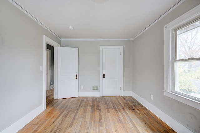 unfurnished bedroom with light hardwood / wood-style floors, multiple windows, and ornamental molding