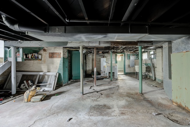 basement featuring a wealth of natural light, gas water heater, sink, and electric panel