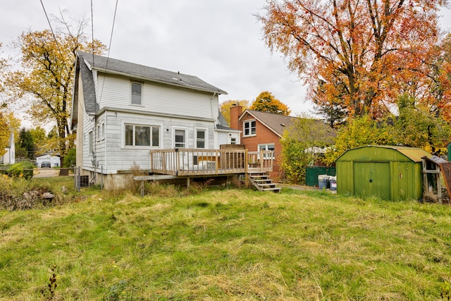 rear view of property featuring a wooden deck, a yard, and a storage shed