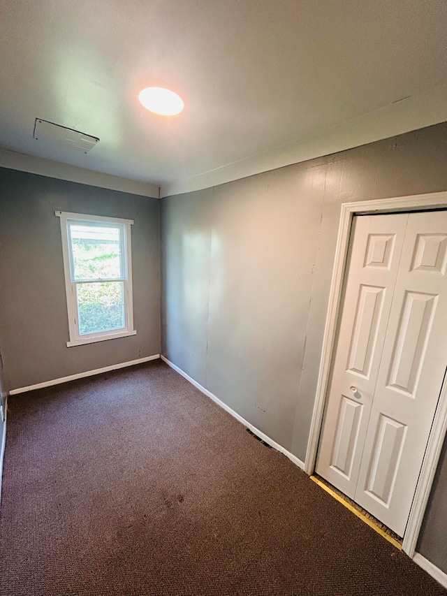 unfurnished room featuring dark colored carpet