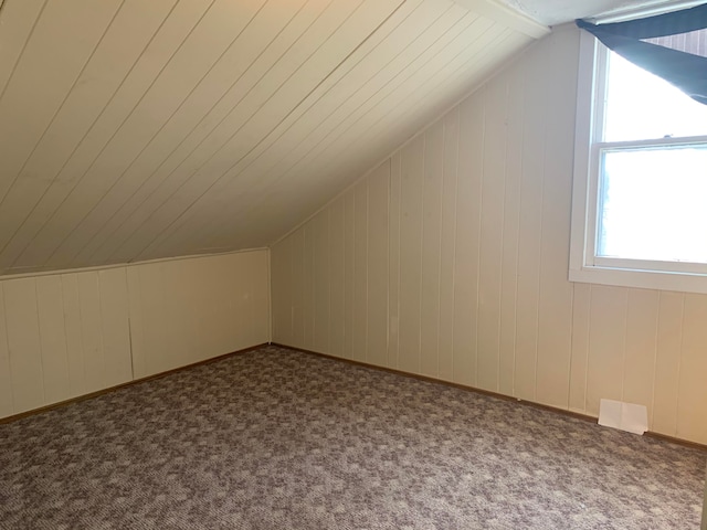 bonus room with carpet flooring, vaulted ceiling, and wooden walls