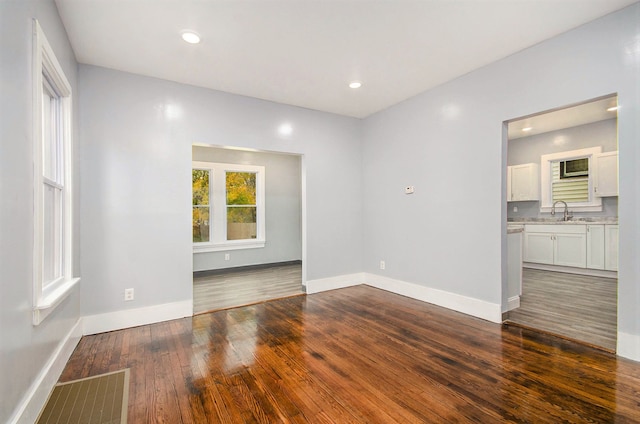 unfurnished room with recessed lighting, dark wood-type flooring, a sink, visible vents, and baseboards