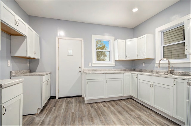 kitchen with white cabinets, light hardwood / wood-style flooring, and sink