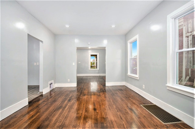 spare room with baseboards, wood finished floors, visible vents, and a healthy amount of sunlight