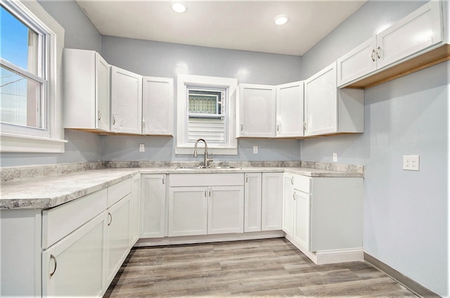 kitchen with white cabinets, a sink, and light wood-style flooring