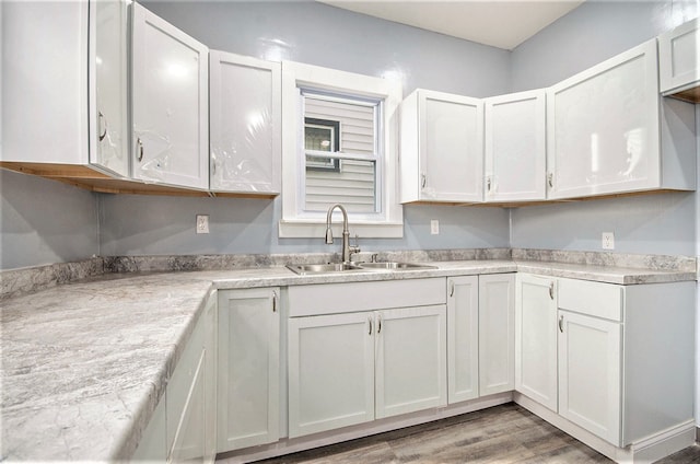 kitchen with light wood-style flooring, white cabinetry, light countertops, and a sink