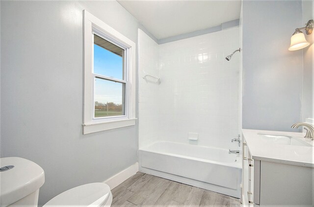 full bathroom featuring hardwood / wood-style floors, vanity, toilet, and tiled shower / bath