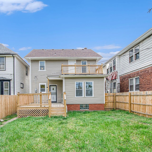 rear view of house featuring a balcony, a fenced backyard, and a lawn