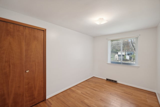 unfurnished bedroom featuring light hardwood / wood-style flooring and a closet