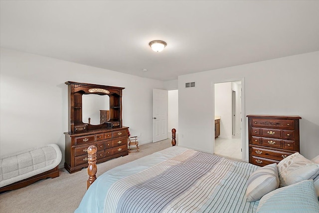 bedroom with connected bathroom and light carpet