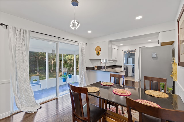 dining area with wood-type flooring, washer / dryer, and sink