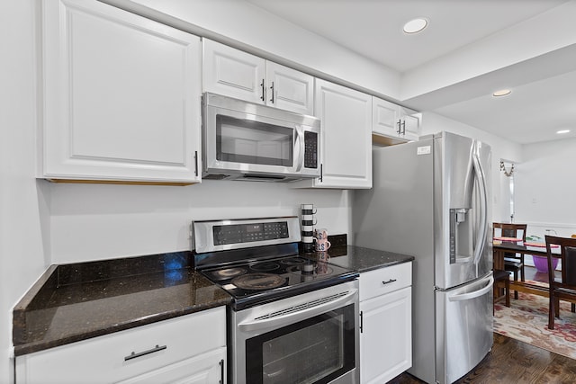 kitchen with stainless steel appliances, white cabinetry, dark hardwood / wood-style floors, and dark stone countertops