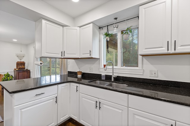 kitchen with a healthy amount of sunlight, white cabinetry, sink, and dark stone counters