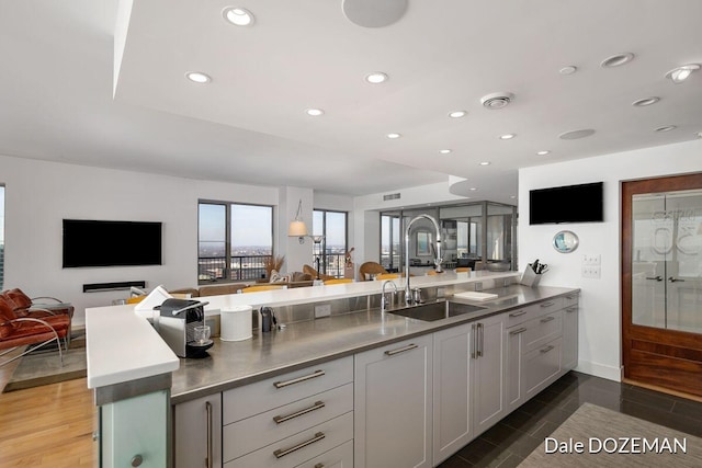 kitchen with hardwood / wood-style floors, stainless steel counters, kitchen peninsula, and sink