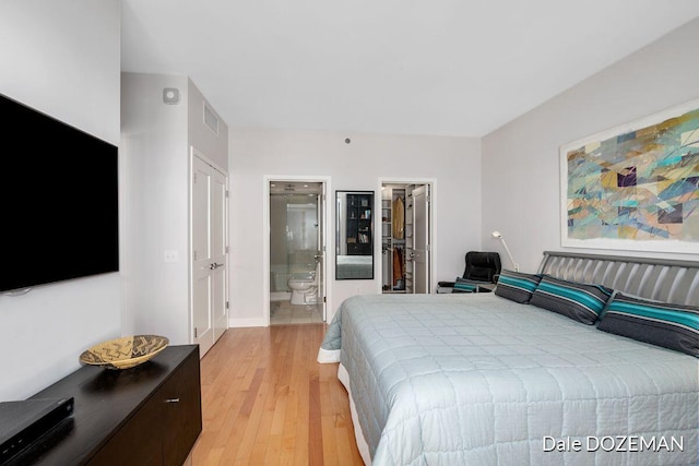 bedroom featuring a walk in closet, ensuite bathroom, light hardwood / wood-style flooring, and a closet