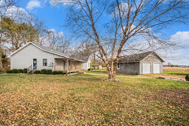 view of yard with a garage, driveway, an outbuilding, and entry steps