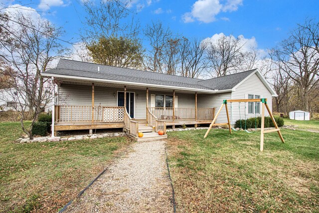 single story home featuring an outbuilding, a playground, a storage shed, a wooden deck, and a front yard