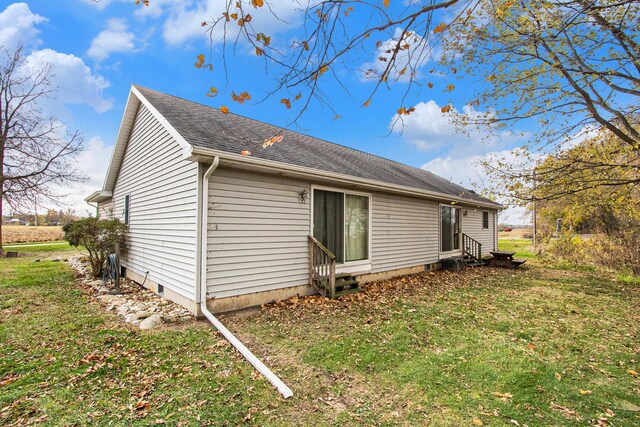 back of house featuring entry steps, a yard, and a shingled roof