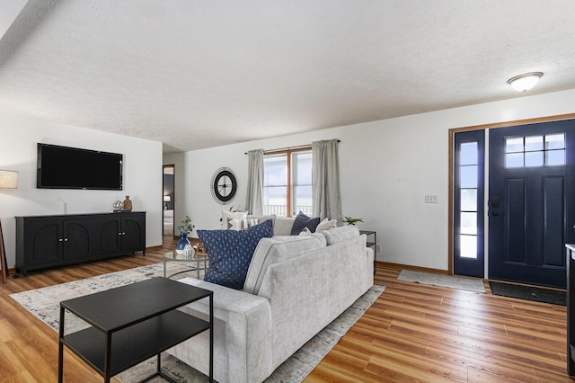 living room featuring a textured ceiling, wood finished floors, and baseboards