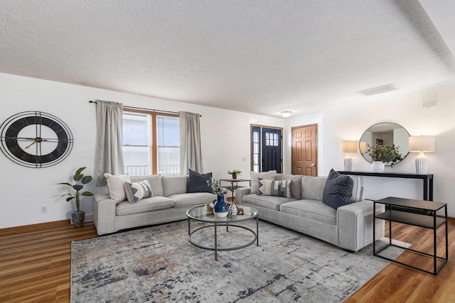 living area with visible vents, a textured ceiling, and wood finished floors