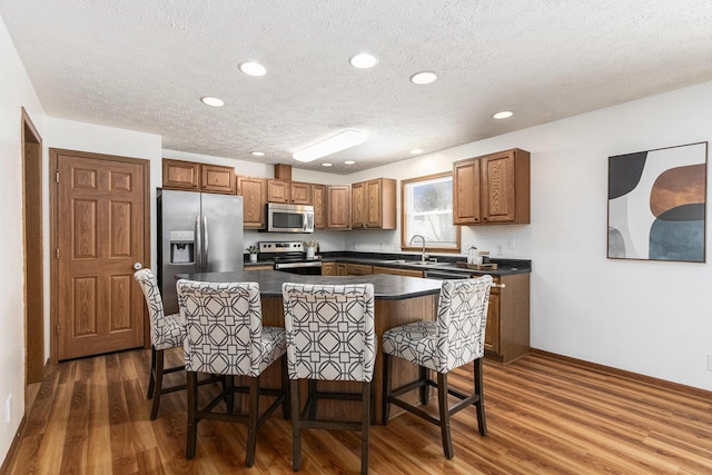 kitchen featuring stainless steel appliances, dark countertops, and brown cabinets