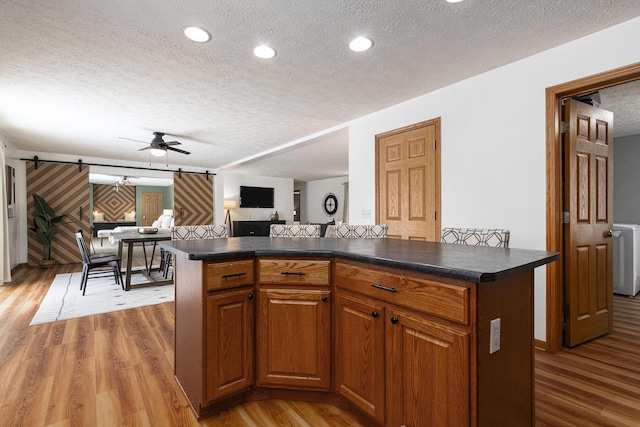 kitchen featuring open floor plan, a barn door, dark countertops, and a kitchen island