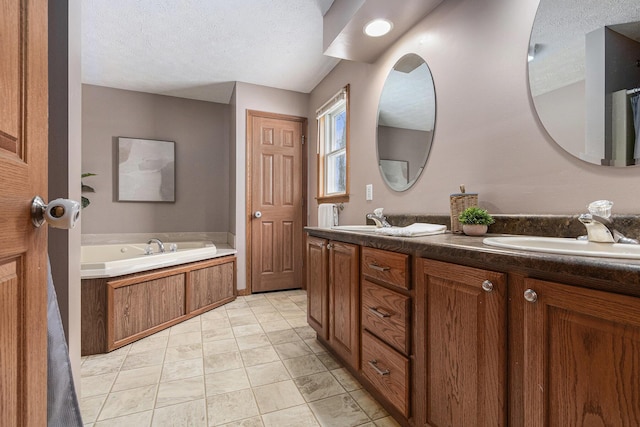 bathroom with double vanity, a sink, a textured ceiling, tile patterned flooring, and a bath