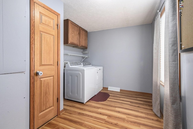 laundry room with visible vents, cabinet space, light wood-style flooring, a textured ceiling, and washer and dryer