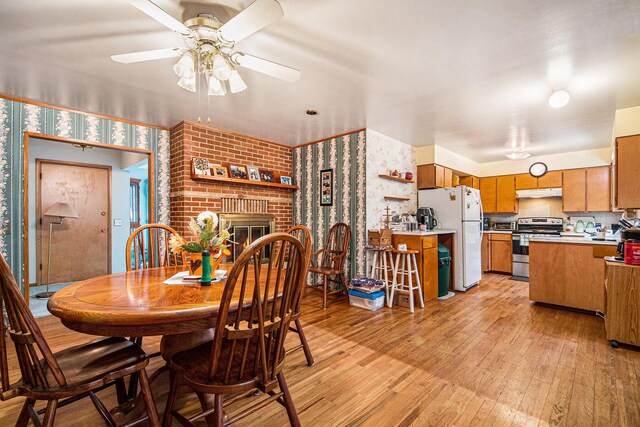288 E 88th St, Newaygo, MI 49337 - dining room featuring wallpapered walls, a ceiling fan, light wood-style floors, and a fireplace