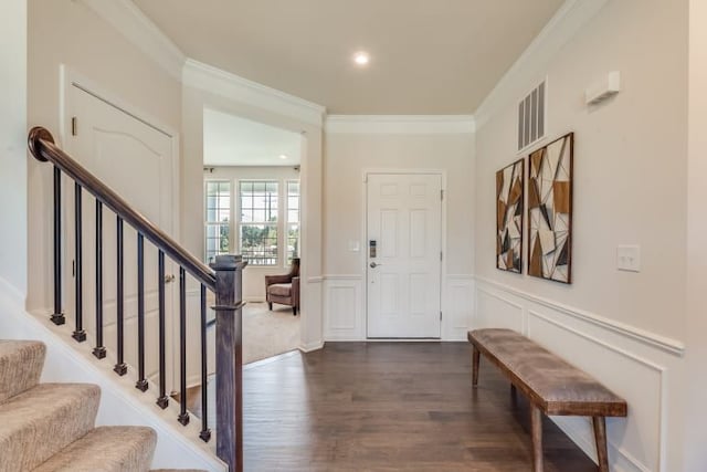 foyer with ornamental molding and dark hardwood / wood-style flooring