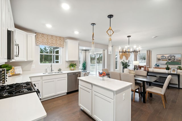 kitchen featuring stainless steel appliances, white cabinetry, a kitchen island, and sink