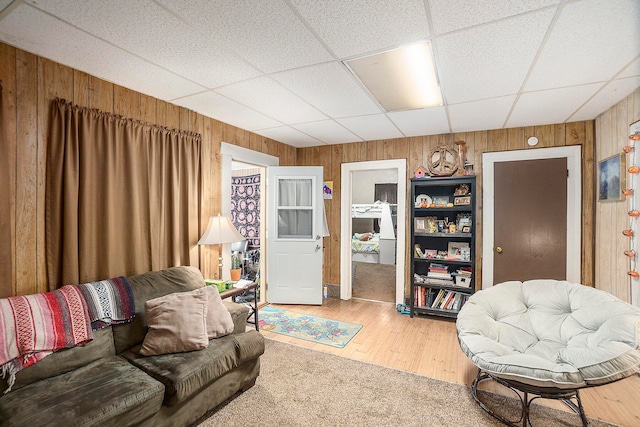 living room with a paneled ceiling, wood walls, and hardwood / wood-style floors