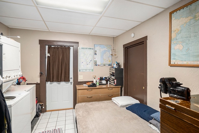 bedroom featuring a paneled ceiling, light tile patterned floors, and stacked washing maching and dryer