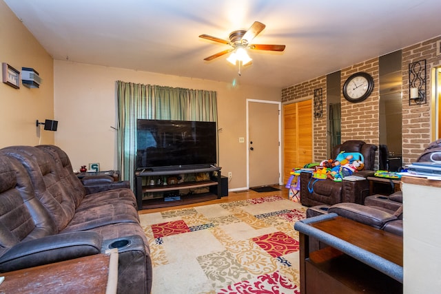 living room with hardwood / wood-style floors, ceiling fan, and brick wall