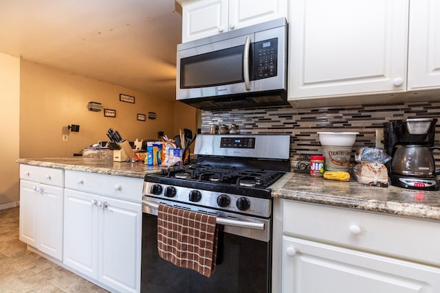 kitchen with tasteful backsplash, white cabinets, and appliances with stainless steel finishes