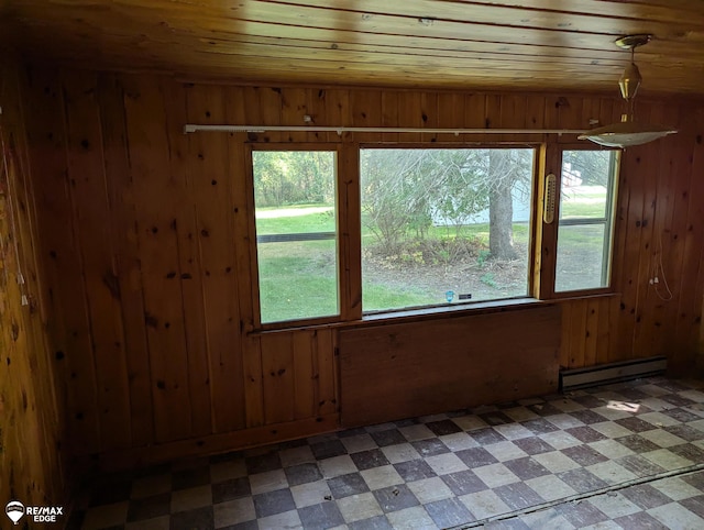 unfurnished room featuring plenty of natural light, wooden walls, and a baseboard heating unit